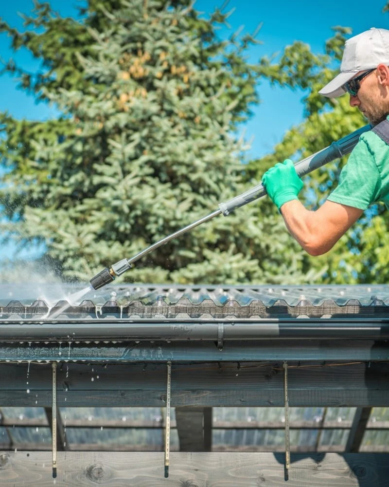 A long-handled tool clearing debris from a gutter