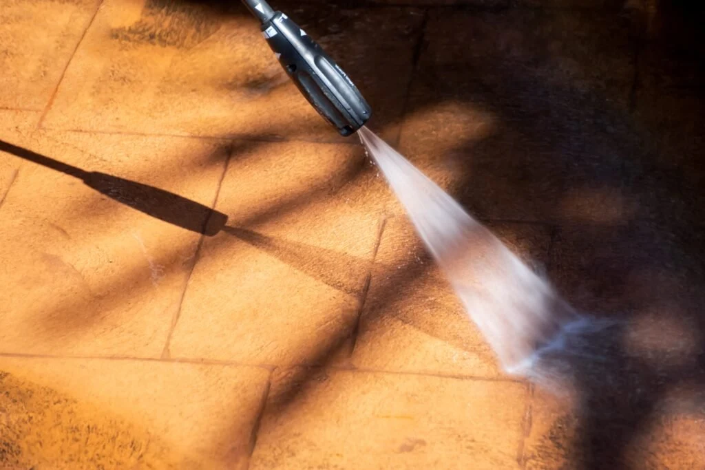 A pressure-washing nozzle cleaning an exterior wood surface