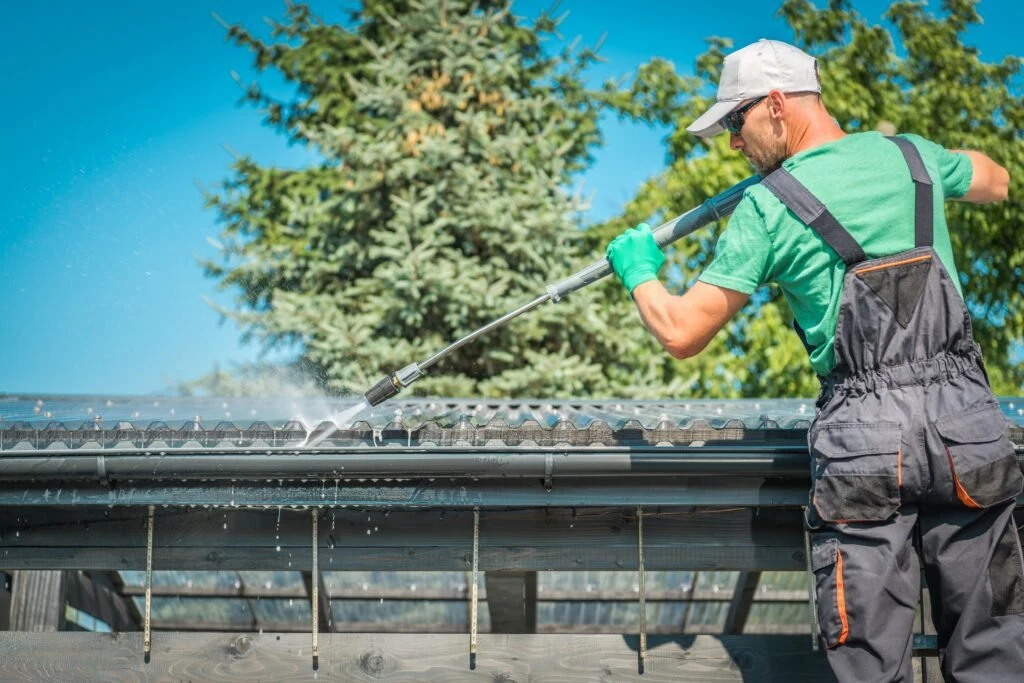 Long-handled gutter cleaning beside trees